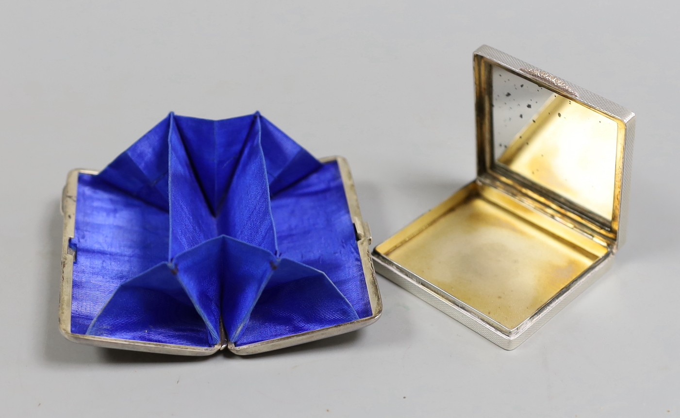 A cased late Victorian silver mounted purse, London, 1883, 82mm, together with a later engine turned silver mounted compact.